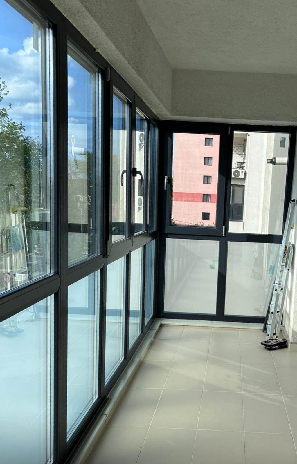 Interiorul unui balcon de bloc închis cu tâmplărie PVC antracit, cu canate sus și ochiuri fixe jos