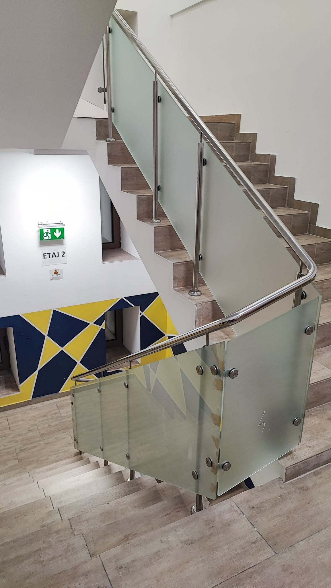 Palier de scară cu balustradă din panouri de sticlă mată prinse cu rozete pe stâlpi din inox, cu mână curentă rotundă din inox