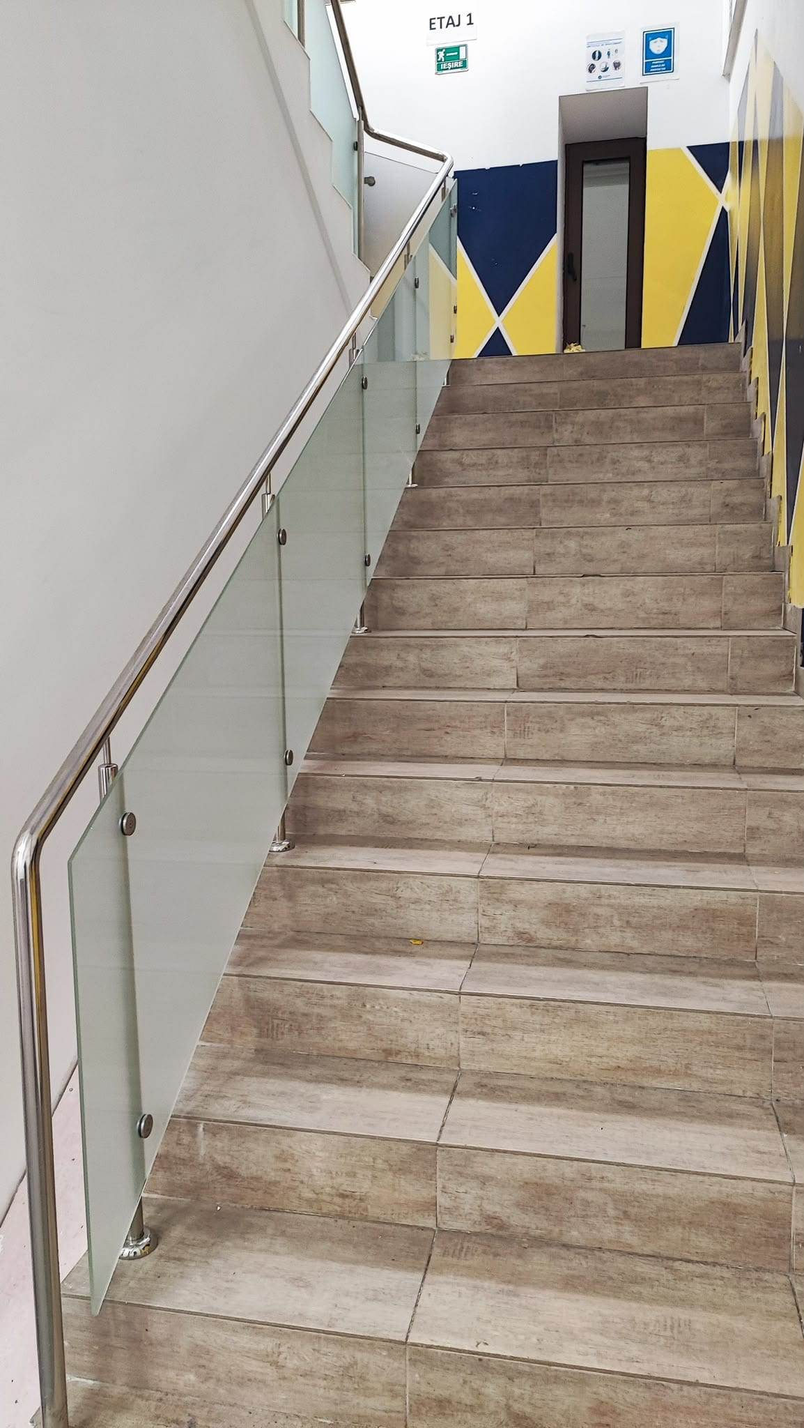 Rampă dreaptă de scară cu balustradă din sticlă mată și mână curentă din inox, văzută de jos