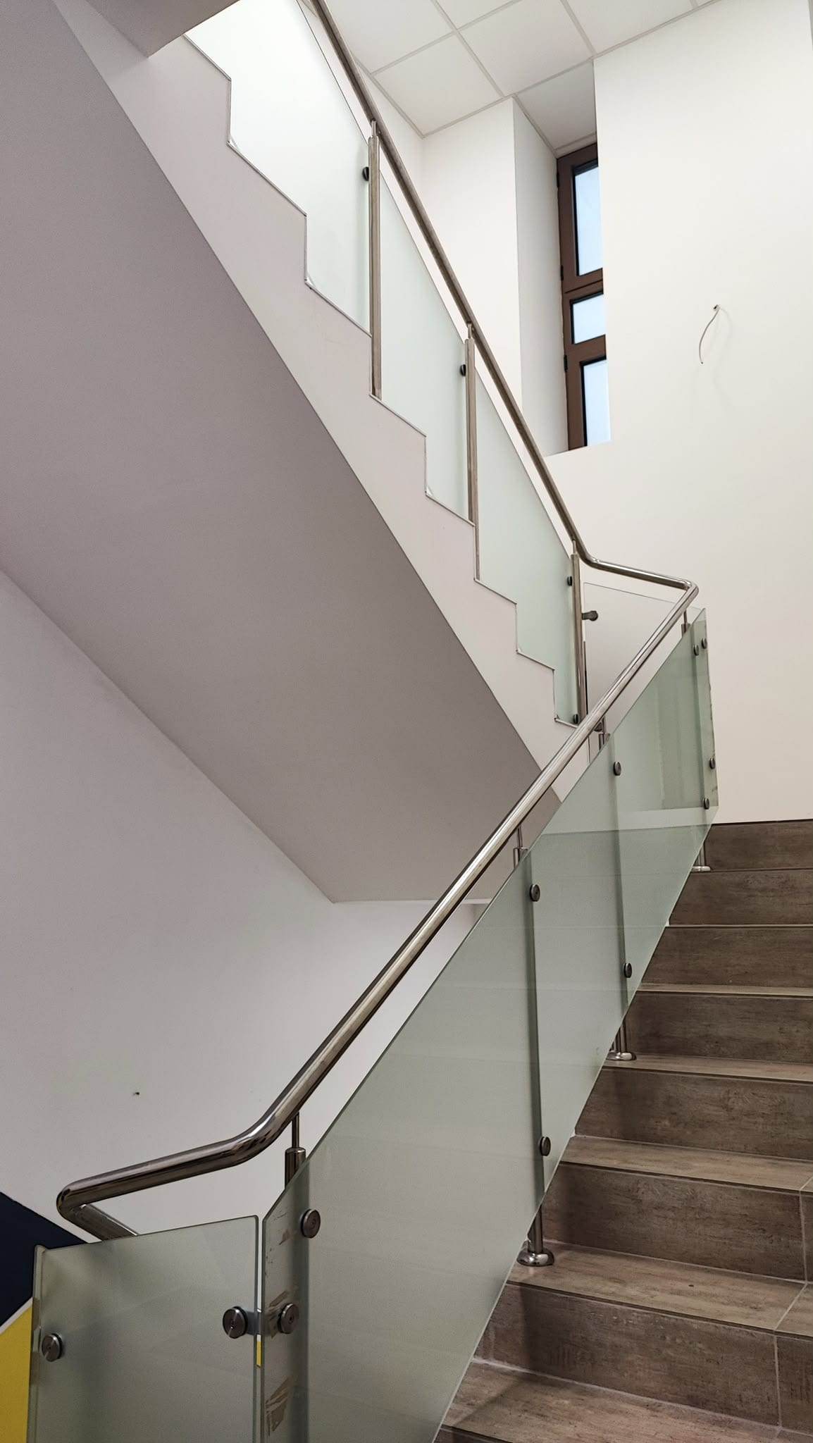 Casa scării cu balustradă din inox și sticlă mată pe două rampe, cu întoarcerea mâinii curente la palier