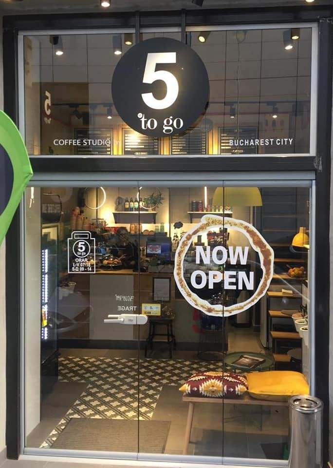 Front de cafenea cu vitrină mare din sticlă și ușă de sticlă, cu semnul 5 to go deasupra
