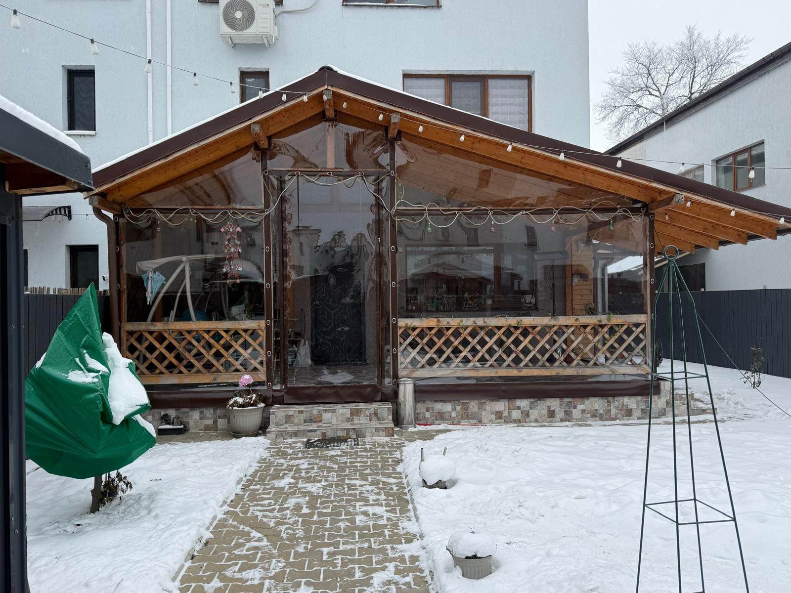 Fața unei terase din lemn închisă cu panouri de folie cristal deasupra balustradei în romburi, Green City, 1 Decembrie