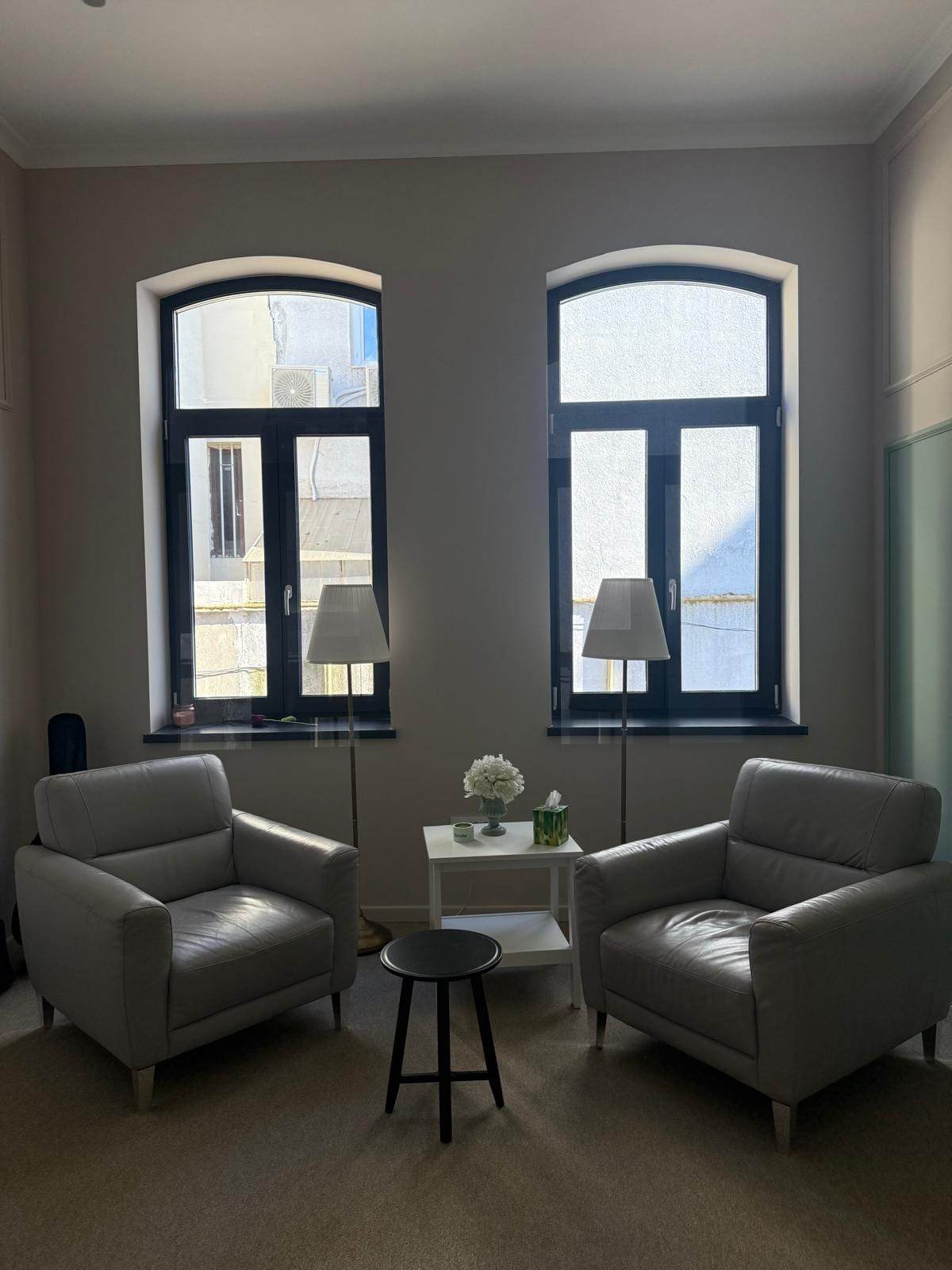 Două ferestre PVC gri antracit cu arc într-o cameră cu fotolii gri și lămpi de podea, după renovarea clădirii de pe Șos. Viilor