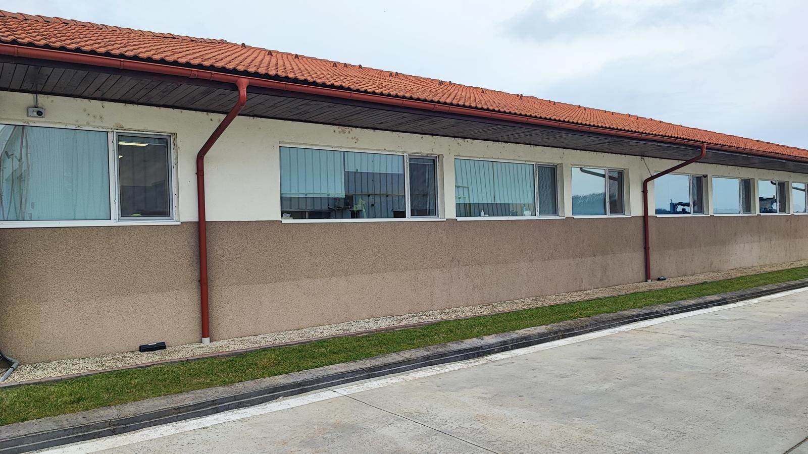 Șir de ferestre PVC albe late sub streașina cu țiglă roșie, pe fațada sediului Corteva România