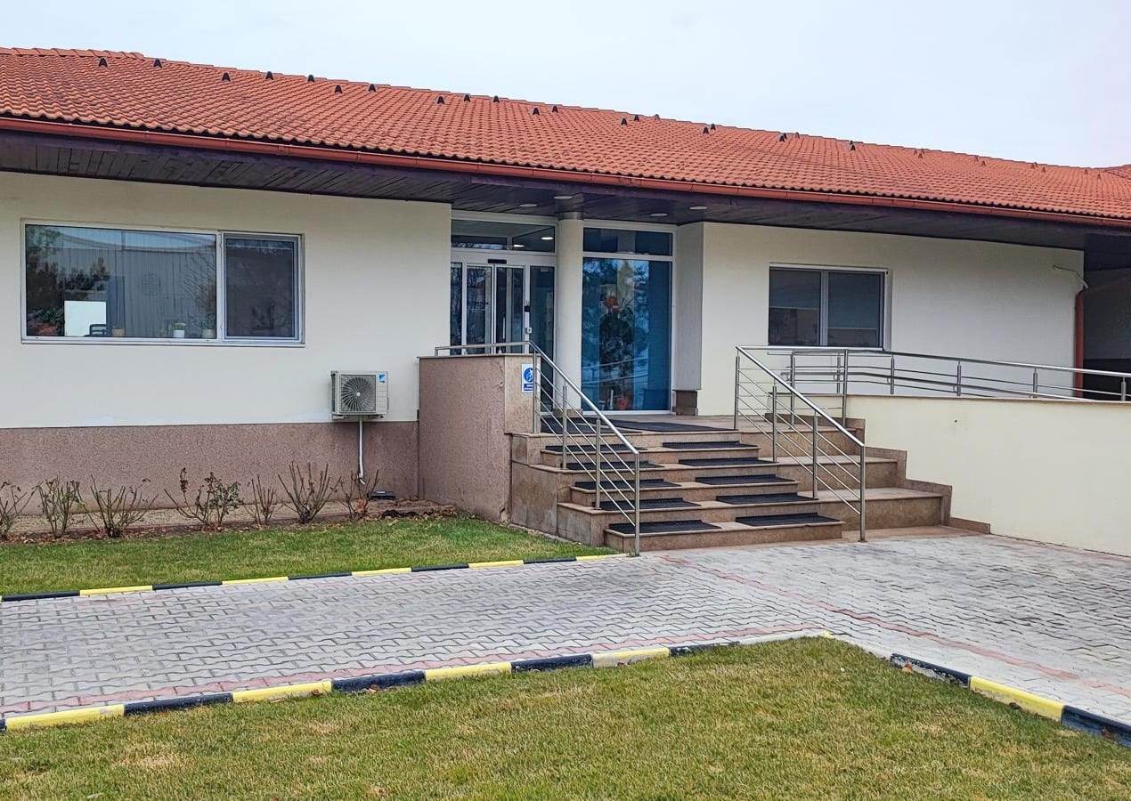 Intrarea sediului Corteva România cu scări și balustradă din inox, cu ferestrele PVC albe de o parte și de alta
