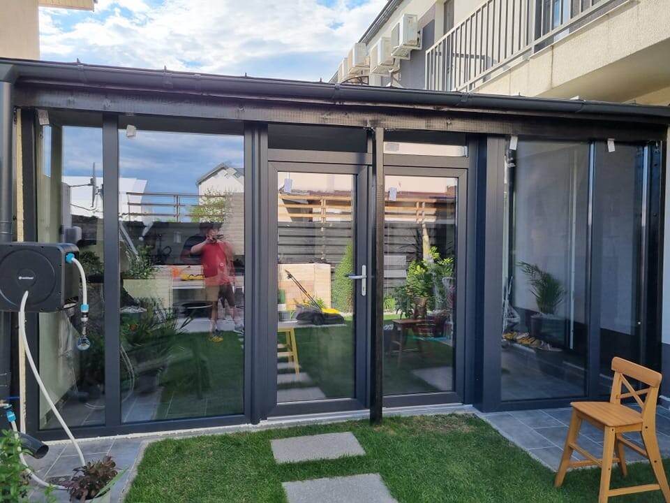 Terasă închisă cu profile de aluminiu antracit și ușă de sticlă spre grădină